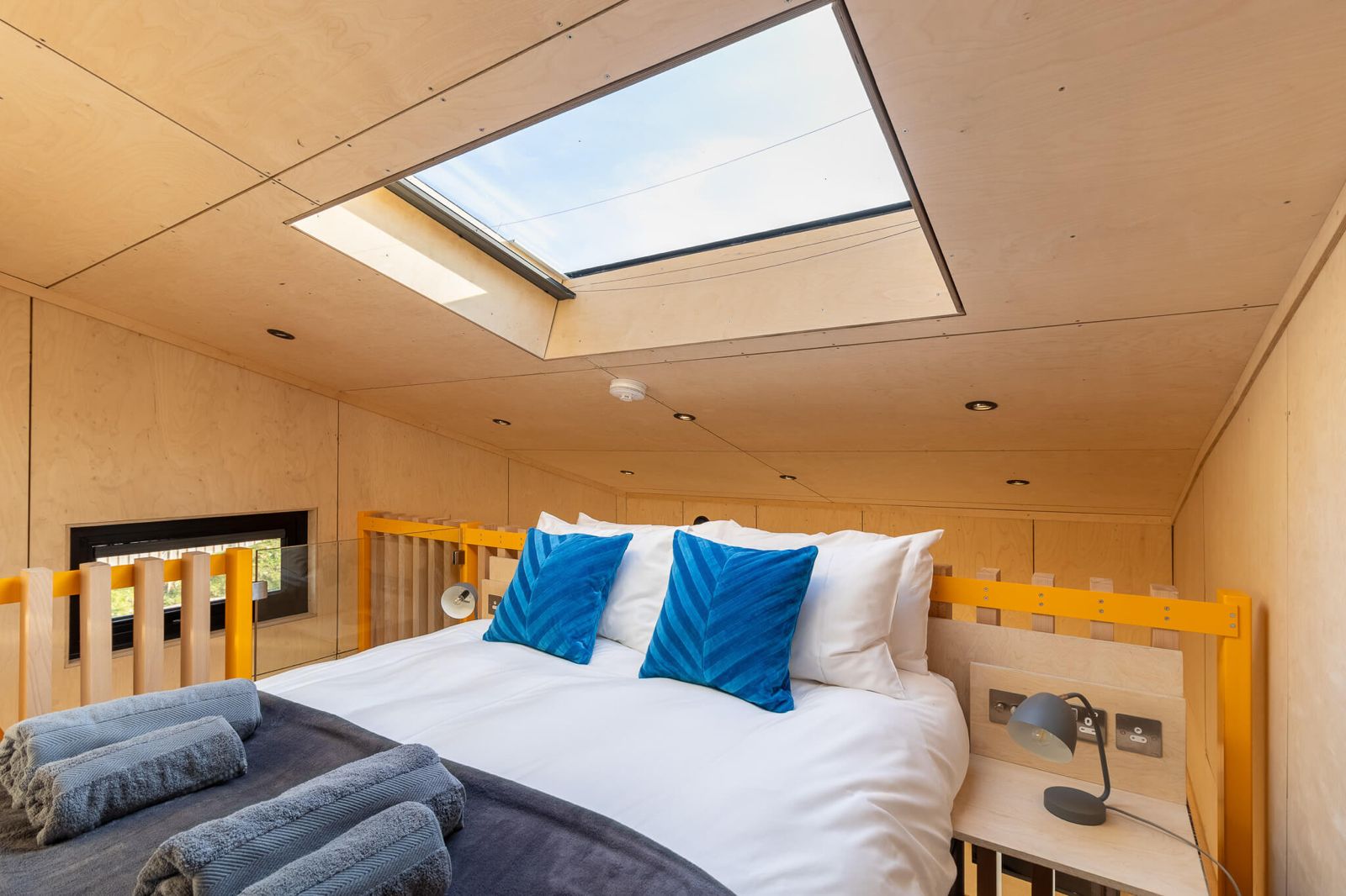 Stylish mezzanine bedroom within a cabin, designed to maximize space and charm. This loft setup is perfect for how to build cabins for Airbnb or retreat accommodation on your land, offering guests a unique and bright sleeping experience with a skylight.