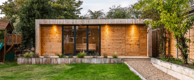 Interior view of a premium insulated garden office featuring a modern corner desk, professional lighting, and expansive outdoor views.