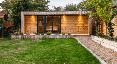 Interior view of a premium insulated garden office featuring a modern corner desk, professional lighting, and expansive outdoor views.