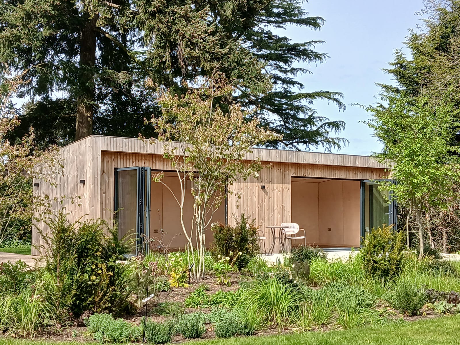 An extra-large garden pod in Cambridge featuring contemporary vertical timber cladding and expansive double-glazed windows.