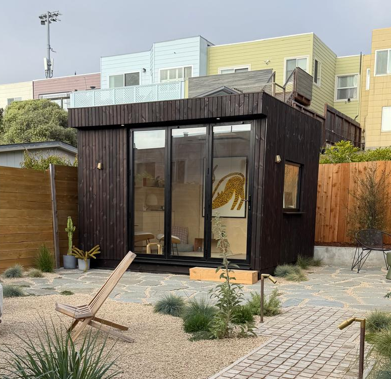 A modern OKO120 backyard office pod with premium wood cladding, nestled neatly into a residential garden lawn.