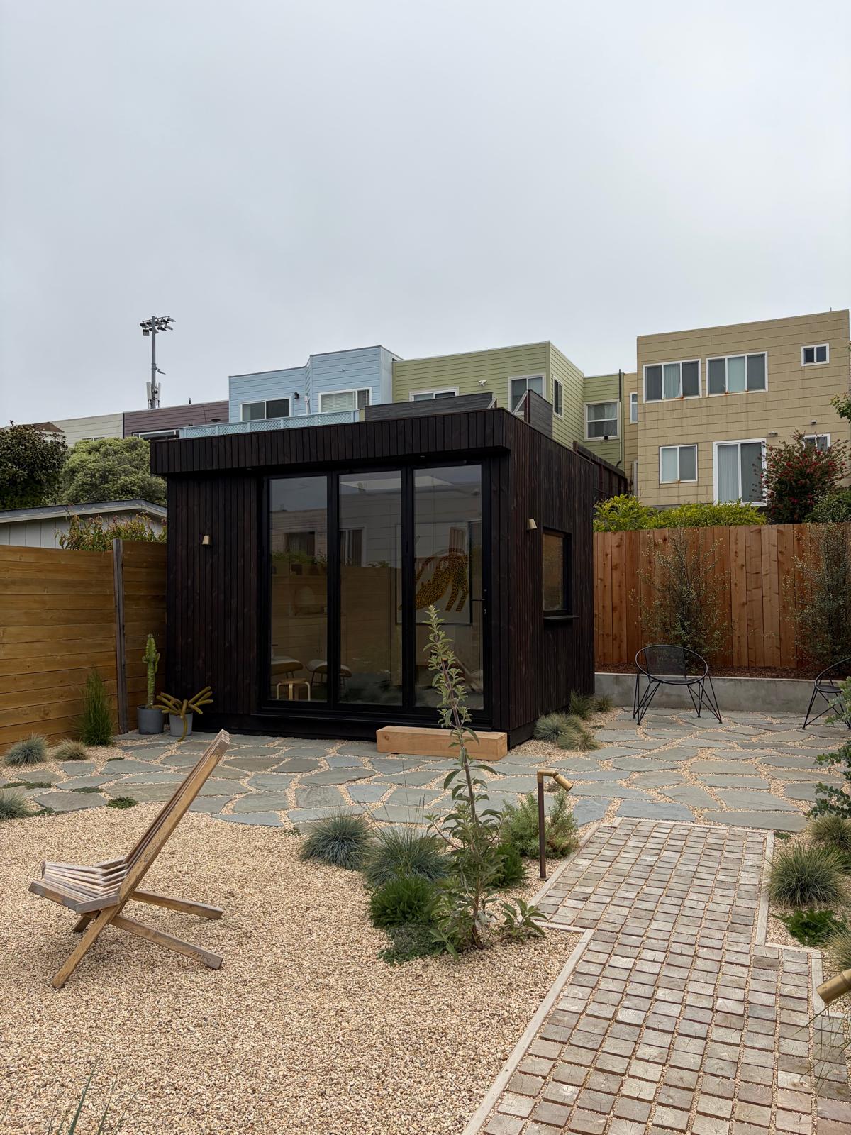 Wide external shot of a premium OKO120 backyard office pod with closed glazing, standing as a striking modern focal point on a manicured lawn.