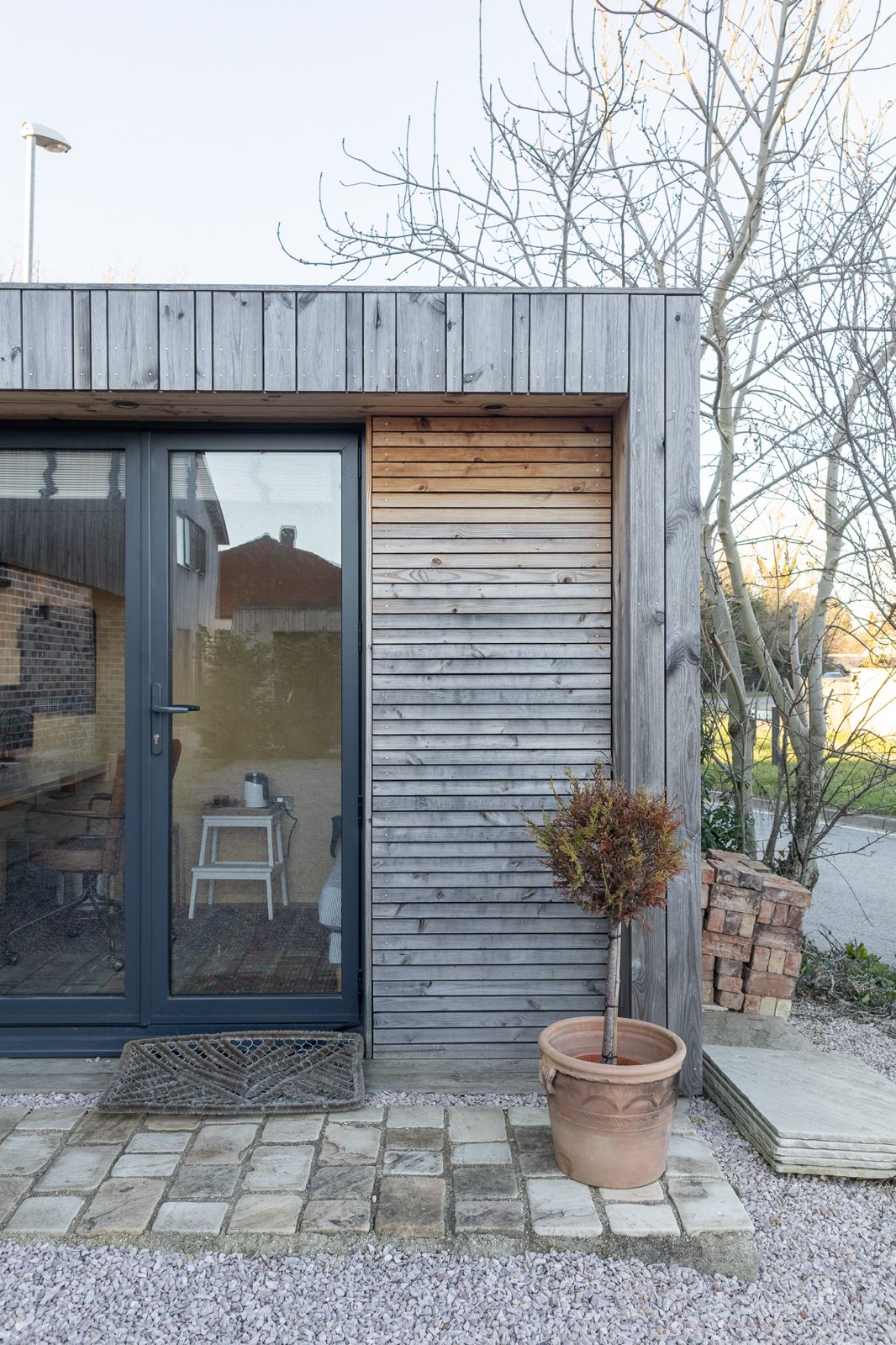 A bespoke contemporary garden office pod integrated into a residential garden, featuring a striking geometric profile and premium cedar cladding.