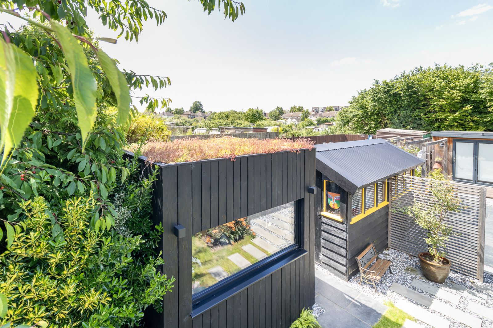 An external view of high-end sedum roof garden pods showing the vibrant green roof blanket seamlessly matching a landscaped residential lawn.