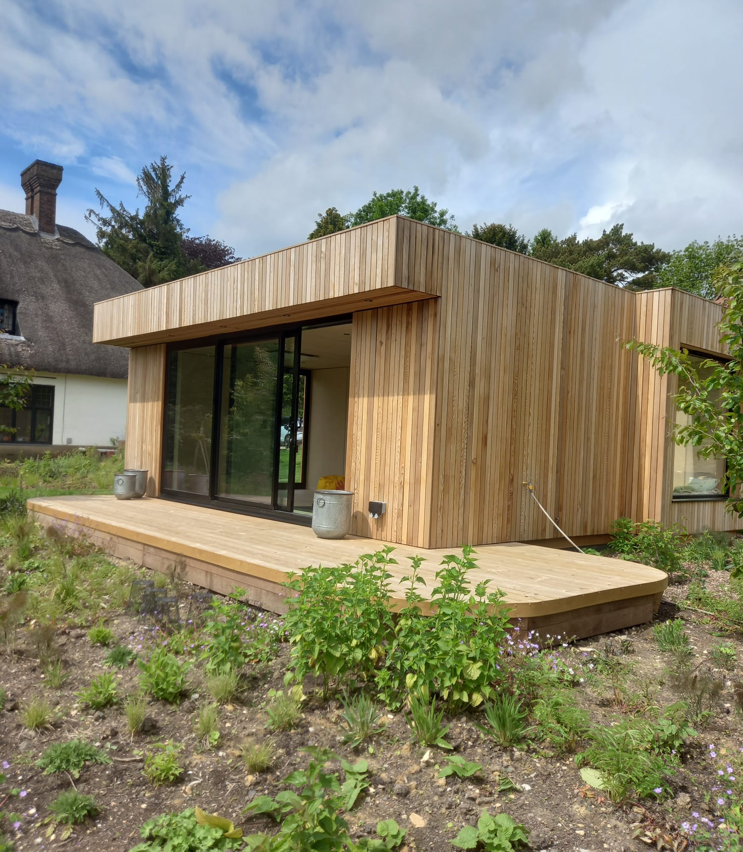 Bold front view of a modern luxury garden annex pod with expansive glazing, timber slats, and sleek architectural symmetry.