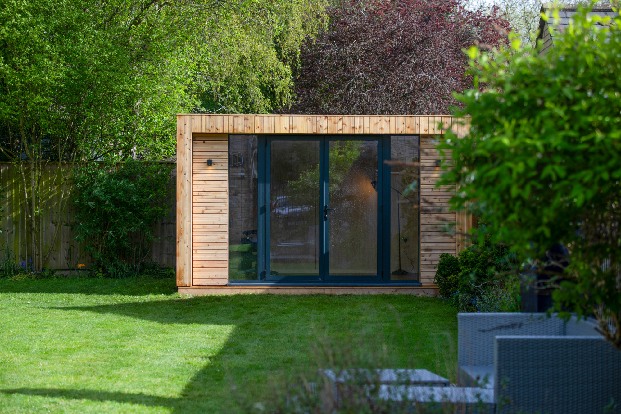A freestanding backyard work studio with natural wood siding, positioned carefully to meet the property line setback rules required for a Colorado backyard office permit.