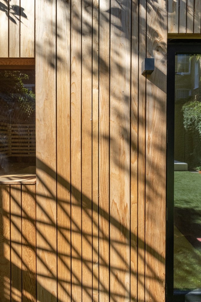 Sunlight filtering across a rich natural wood siding layout, highlighting the texture and warmth of the best backyard room cladding options for accessory dwelling units.