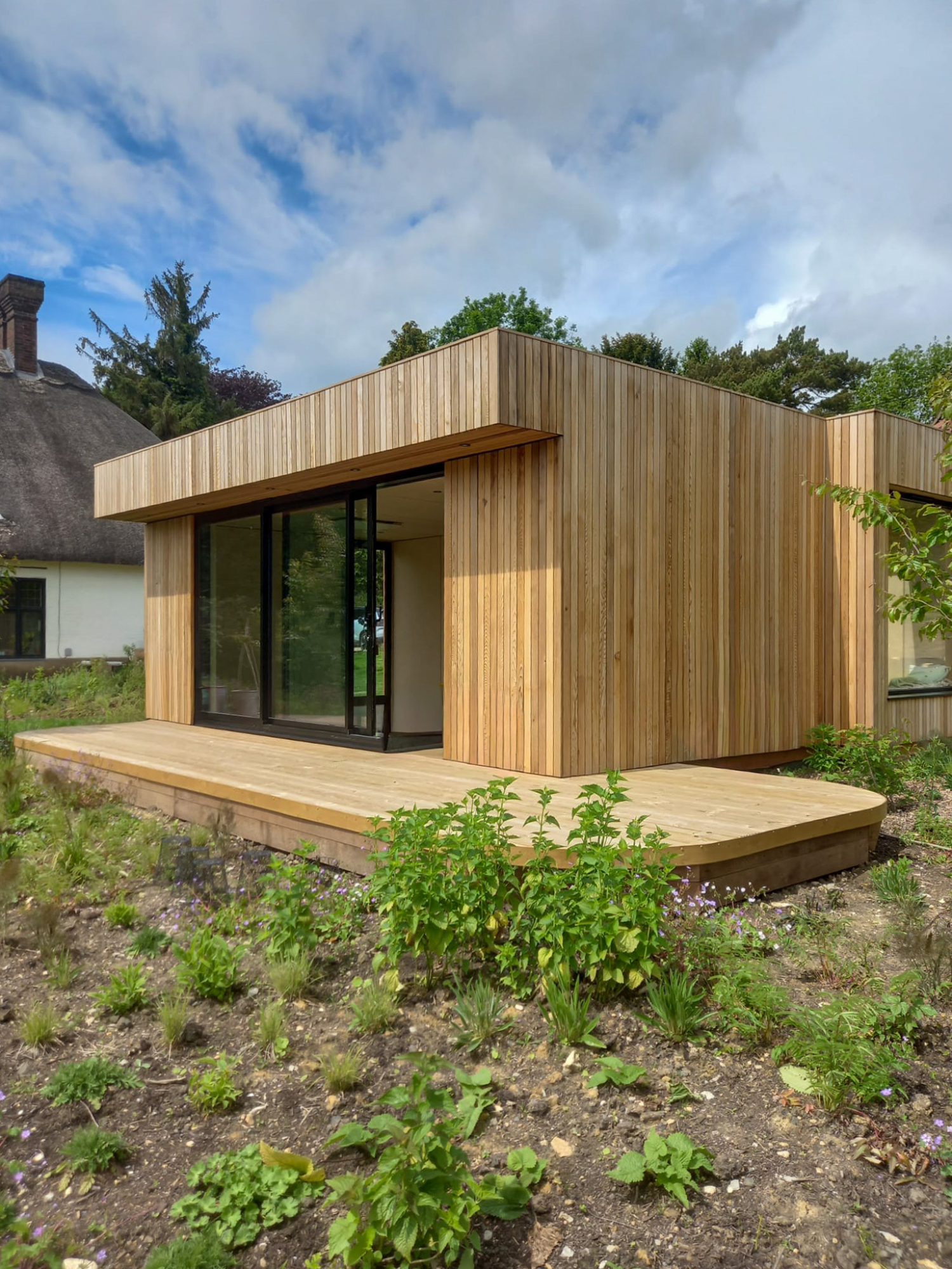 Bold front view of a modern luxury garden annex pod with expansive glazing, timber slats, and sleek architectural symmetry.