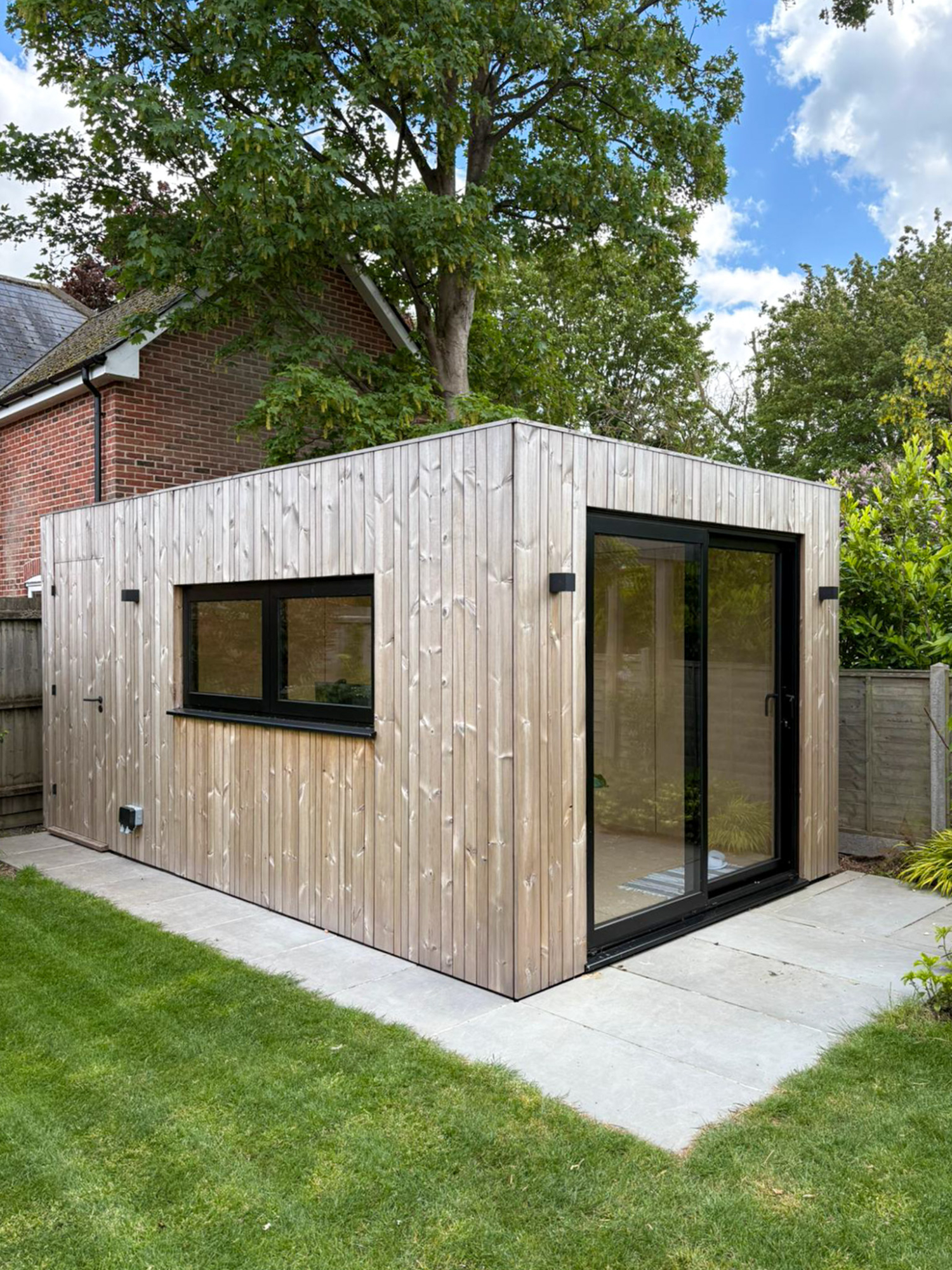 Inside a modern, insulated Cambridge garden office pod featuring a spacious workspace layout, wood cladding, and a comfortable armchair.