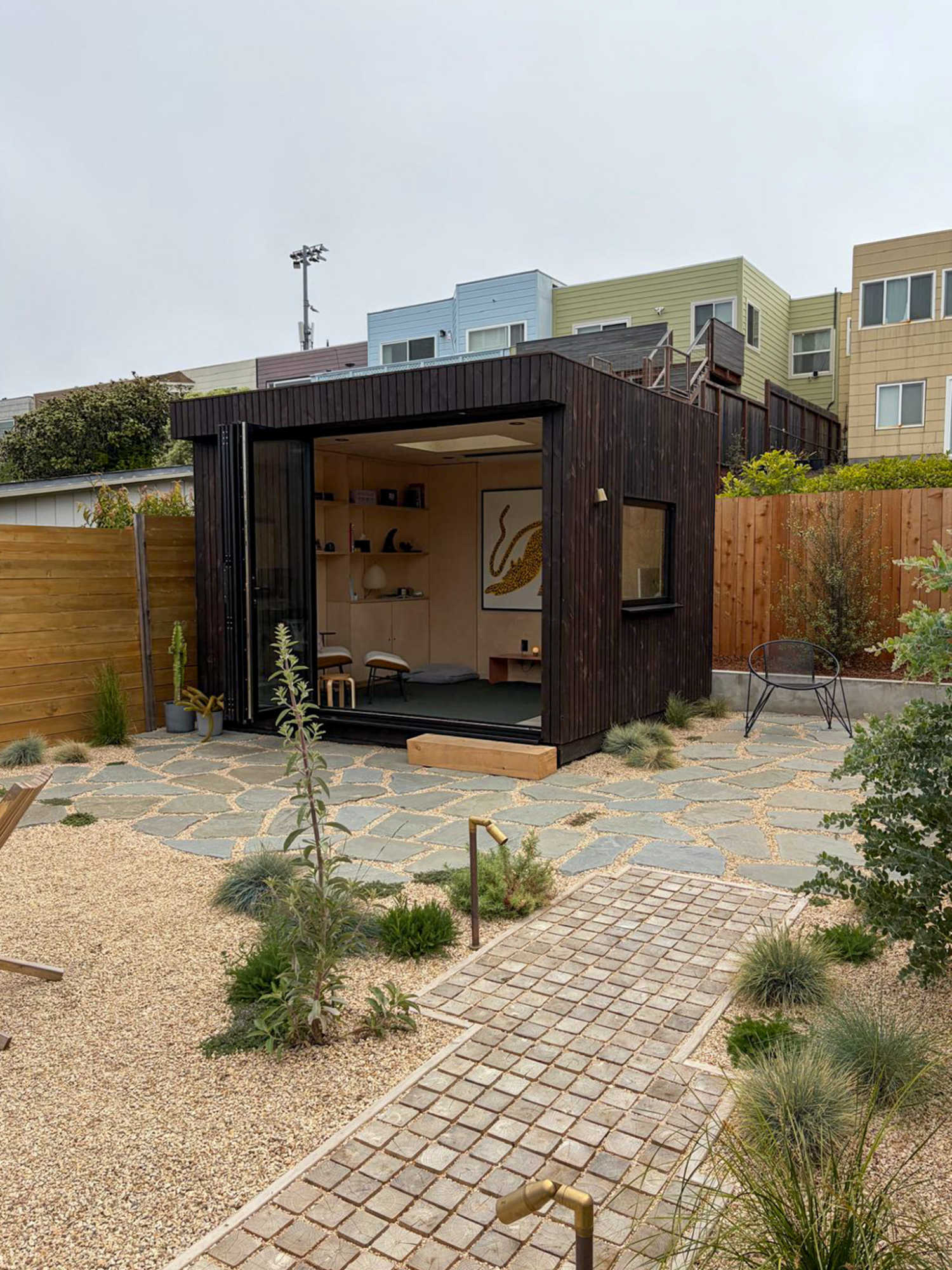 Wide external shot of a premium OKO120 backyard office pod with closed glazing, standing as a striking modern focal point on a manicured lawn.
