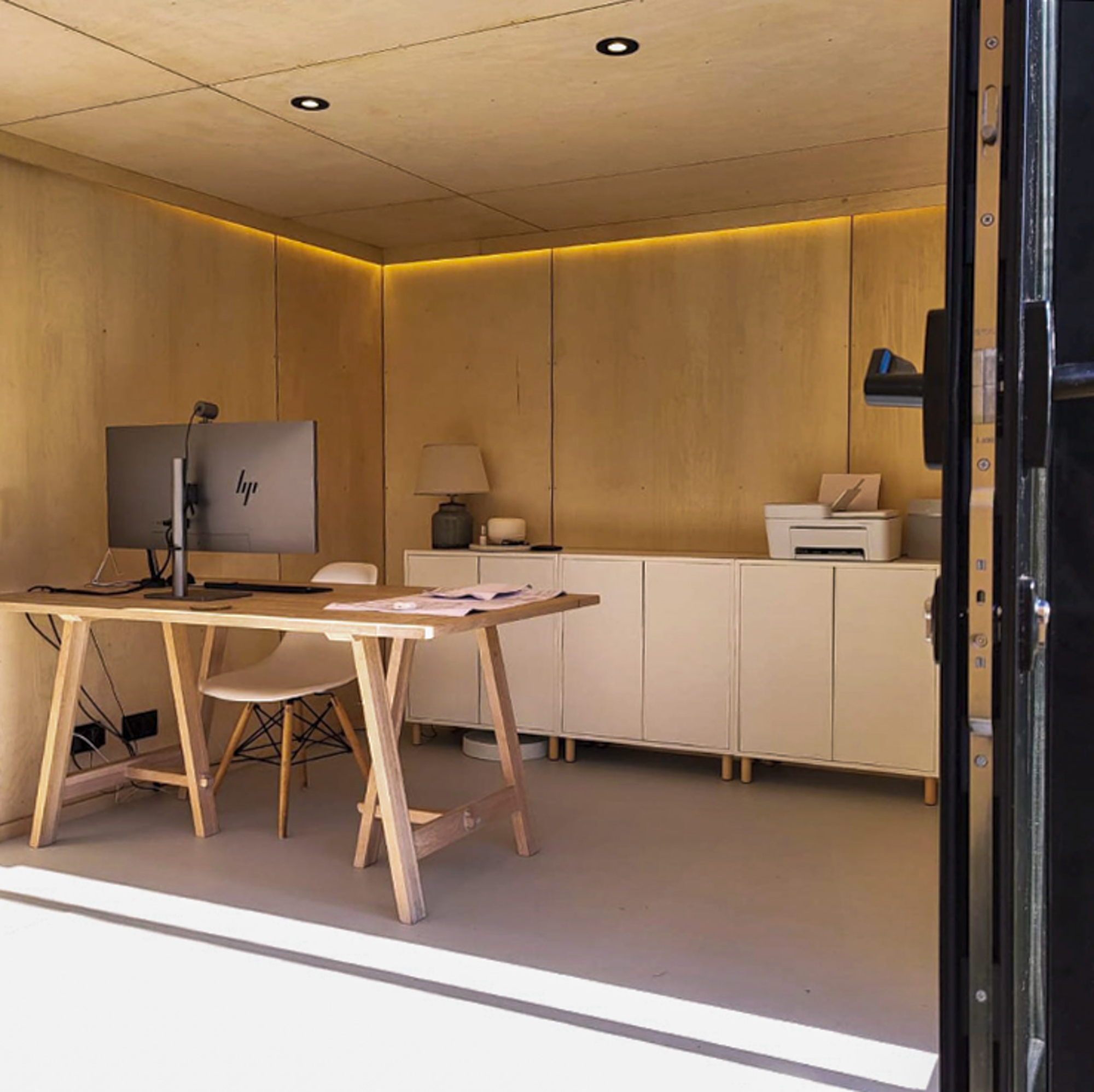 A spacious, minimalist desk and storage configuration built inside a standalone yard pod, compliant with a residential Colorado backyard office permit.