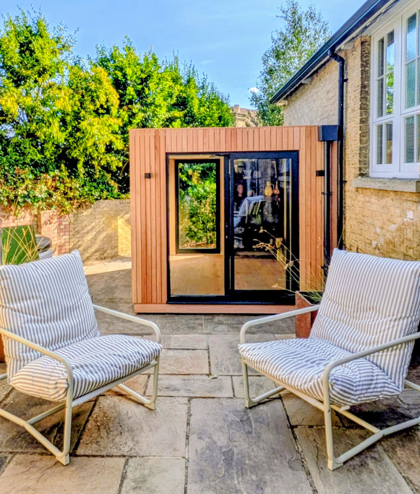 Full exterior shot of a freestanding prefabricated classroom pod with glass doors set up in an outdoor courtyard seating area.